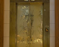 PVD-beschichtete Aufzugstüren in Gold mit Glasperlenoberfläche und reflektierenden Linien