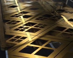 Architekturplatte aus PVD-beschichtetem Edelstahl in Gold mit reflektierenden, gebürsteten Oberflächen und Laserausschnitten